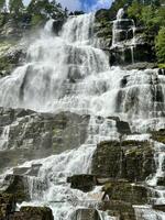 A waterfall is surrounded by rocks and trees on a beautiful sunny day photo