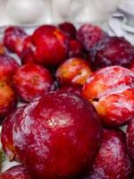 a pile of fresh ripe plums sell in open market. Neatly arranged snowflake plums photo