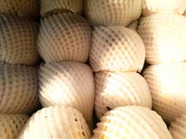 pile of fresh pears wrapped in fruit net at market photo
