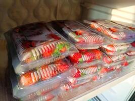 Strawberries from local market, Fresh strawberries picked from home garden in a tray, Red ripe strawberries in plastic tray and packed in clear plastic bag for sale photo
