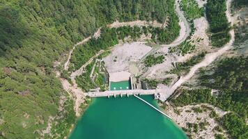 Aerial view of hydro dam in lush forest with turquoise water below, highlighting serenity and engineering of clean energy infrastructure video