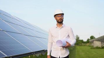 Solar power plant with engineer in protective helmet walking and examining photovoltaic panels. Concept of alternative energy and its maintenance video