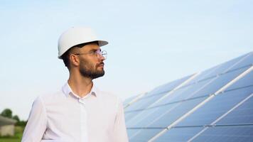 Solar power plant with engineer in protective helmet walking and examining photovoltaic panels. Concept of alternative energy and its maintenance video