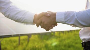 Two engineers, investors or businessmen shaking hands after discussion on background of photovoltaic solar panels, close up video