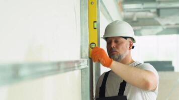 A man builder measures of the vertical deviation of plasterboard wall. Bubble level ruler video