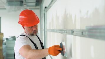 A uniformed worker applies plaster to the drywall wall. Putty of joints of drywall sheets video