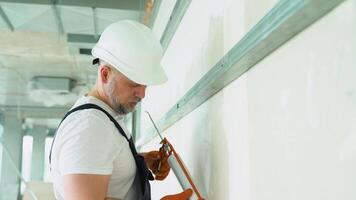 Worker in uniform is applying polyurethane foam to fill gap on drywall wall video