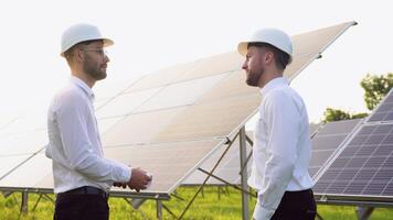 Two engineers, investors or businessmen shaking hands after discussion on background of photovoltaic solar panels video