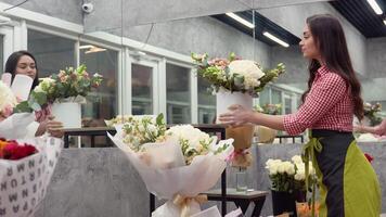 Cheerful charming young woman florist chooses a bouquet of flowers in flower shop video