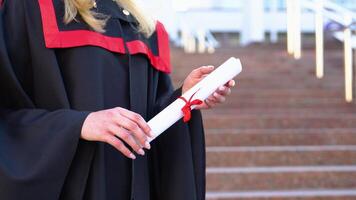 Diploma with a red ribbon in hand on university background video