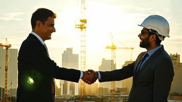 Businessmen and engineer shake hands on a deal with view of The background of a large construction site has beautiful sunlight. video
