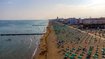 Aerial view of Jesolo beach, near Venice in Italy, coast with sunset. Adriatic Sea in the Mediterranean with beaches full of tourists on holiday and traveling in summer. Top view of umbrellas, hotels. photo