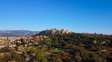 Rock of the Acropolis of Athens seen from afar. Symbol of ancient greece with blue sky background. Ancient architecture of Greek civilization. Ancient remains that attract tourists traveling in Grecce photo