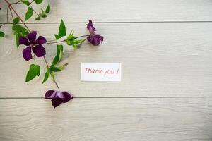 branch of blooming purple clematis, on a light wooden table photo