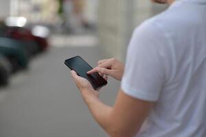 A man on the street using a smartphone. Mobile phone in hands close-up. photo