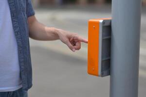 Close-up of a man pushing a crosswalk signal button on a traffic light at a pedestrian crossing. Safely cross road by green traffic light concept photo