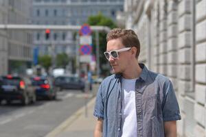 A man wearing sunglasses on the street in Vienna at the background of traffic jam. The concept of hot sunny weather in the city. A man suffers from the heat photo
