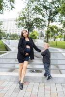 Pregnant mother and her little son walking and funny spending time together photo