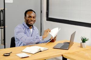 Man sitting at desk holding paper photo