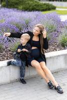 Pregnant mother and her little son spending time together in the park, hugging and smiling photo