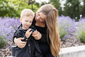 Pregnant mother and her little son spending time together in the park, hugging and smiling photo
