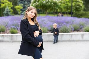 Pregnant mother and her little son walking and funny spending time together photo