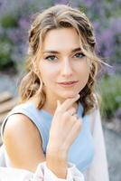 A Woman With Striking Blue Eyeshadow Elegantly Poses in a Vibrant and Lush Summer Garden, Exuding Beauty and Grace photo