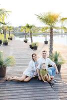 A Charming Family Portrait Captured Against the Backdrop of a Serene Wooden Deck Overlooking a Peaceful Lake photo