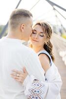 A Loving Couple Is Seen Embracing Each Other on a Beautiful Bridge on a Sunny Day, Surrounded by the Warmth of the Sun photo