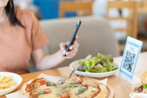 Woman use smartphone to scan QR code to pay in cafe restaurant with a digital payment without cash. Choose menu and order accumulate discount. E wallet, technology, pay online, credit card, bank app. photo
