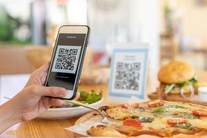 Woman use smartphone to scan QR code to pay in cafe restaurant with a digital payment without cash. Choose menu and order accumulate discount. E wallet, technology, pay online, credit card, bank app. photo