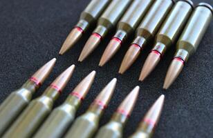 Bullets lined up with heads to heads on black silk velvet surface angle view photo