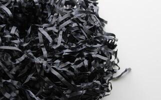 Bunch Of Black Shredded Paper On Clean White Surface. Texture Of Paper Shavings Detailed Stock Photo