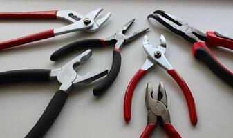 Set Of Different Types Of Mechanics Pliers On White Surface photo