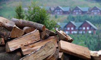Pile Of Firewood With Distant Wooden Cottages On A Background photo