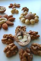 Mix Of Shelled Nuts In Flowers Pattern Isolated On White Vertical Photo