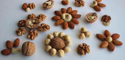 Flowers Pattern made of laid out nuts of different varieties on a white background concept for backgrounds photo