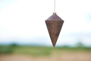 Old plumb bob, plummet or conical iron hanging with rope for measurement level, use for determining perpendicularity . Concept, work tool for construction and carpentry. photo