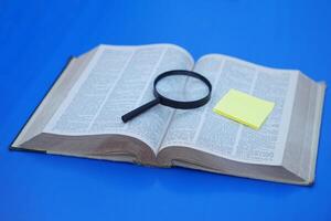 Megnifying glass on page of dictionary book. yellow paper note. Concept, Word searching. Education. photo