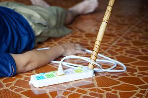 Using wooden stick is moving away the electric plug socket from the unconscious man who lay down on the floor. Concept, Electric Shock. Emergency basic rescue. First Aid photo