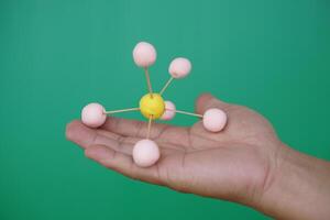 Closeup hand hold DIY molecule structure made from toothpicks and plasticine for teaching. Concept, teaching aids, educational materials. science lesson about molecule. Creative task from learning. photo