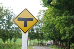 T junction, intersection sign yellow sign. Concept, Transportation symbol. Warning traffic sign to drive slowly and watch out for the intersection ahead. giving direction for transportation. Guidepost photo