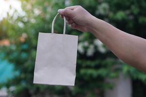 Hand hold brown paper bag. Concept, eco friendly packaging for containing things, can use many times. Reduce, Reuse, Recycle for conserve environment. Reduce plastic garbage campaign. photo
