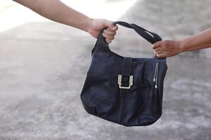 Thief hand snatching the bag from woman. Concept, Criminal pickpocket and crimes. Snatcher stealing handbag. Steal money wallet from other people, type of crime. A thief who picks pockets. photo