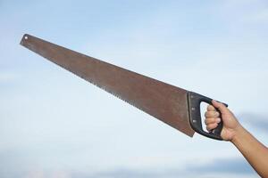 Close up carpenter hand holds old saw. Concept, tool for cutting. Carpentry , woodwork and construction work tool. Carpentry. use for cutting wood. Handsaw for carpenter. photo