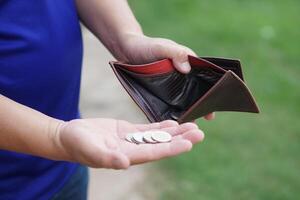 Poor man hold leather wallet with some coins. Concept bad economy, financial crisis, risk on the end of month. Finance management. Pay day. Debt. Broke. Bankrupt. Financial problems. photo