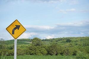 Curved road traffic yellow sign. Warning attention sign Right Winding Road. Concept, Warning traffic sign for Giving direction for transportation and way to go. photo