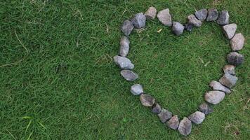 pebbles forming a heart in the green grass, graphic design photo