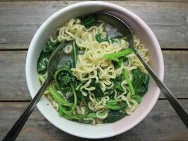 Instant noodle soup with vegetables in a bowl on a gray background photo