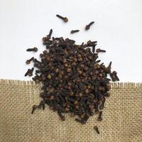 Pile of cloves spice isolated on burlap fabric and white background. The view from top. photo